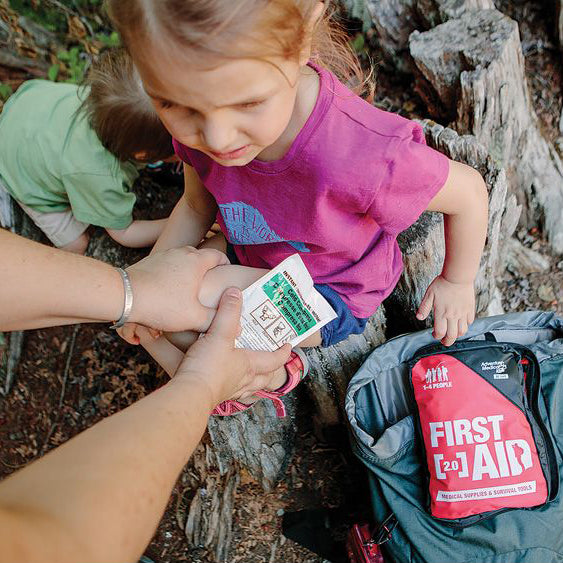 Adult holding a cold compress on a child's hurt knee from Adventure Medical's First Aid Kit 2.0