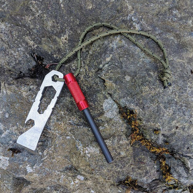 A UCO Fire Striker multi-tool laying on a rock.